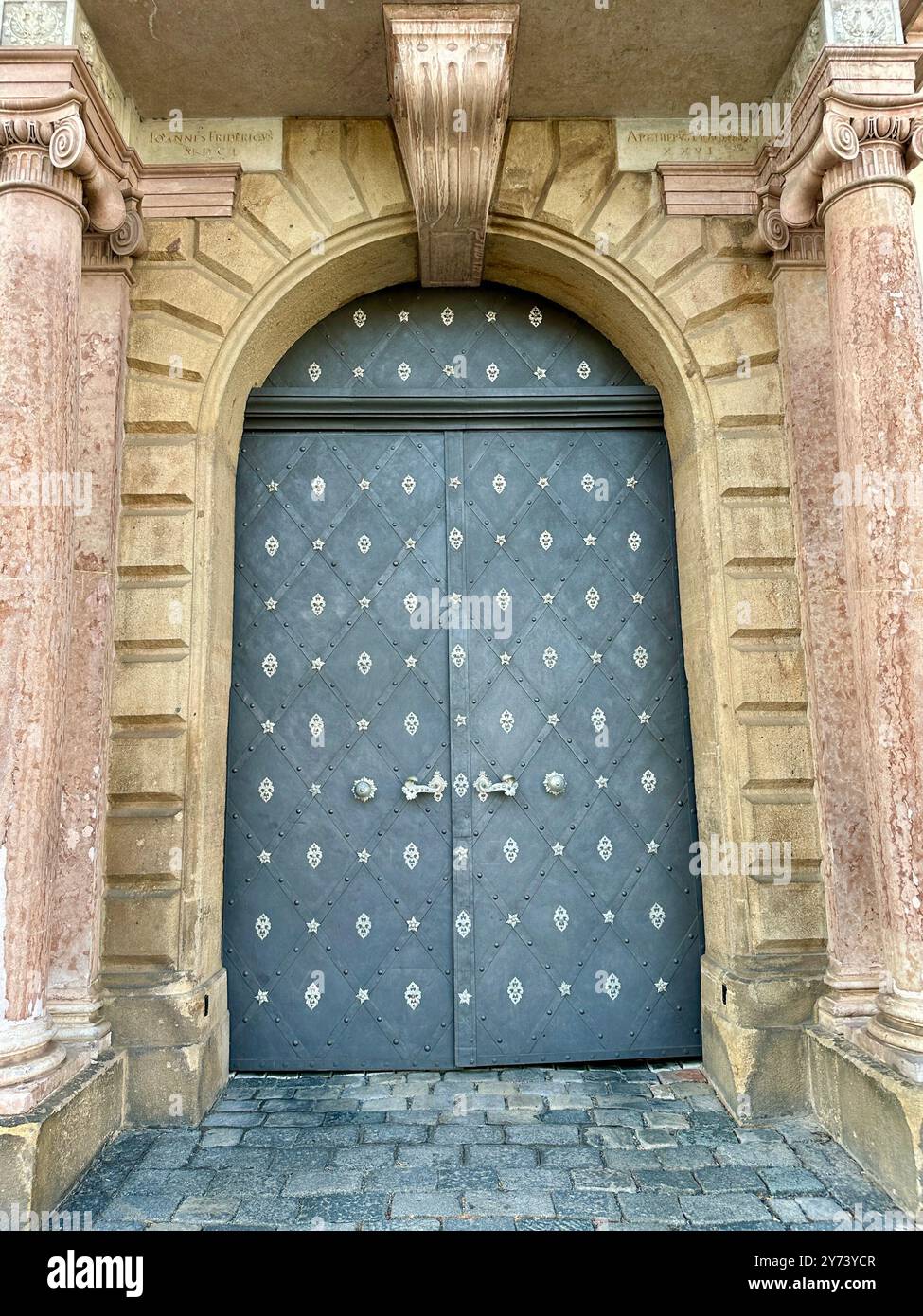 The photograph captures a detailed view of an old medieval gate made of wood and metal, set in the streets of a historic European city. - Smartphone Captured Stock Image