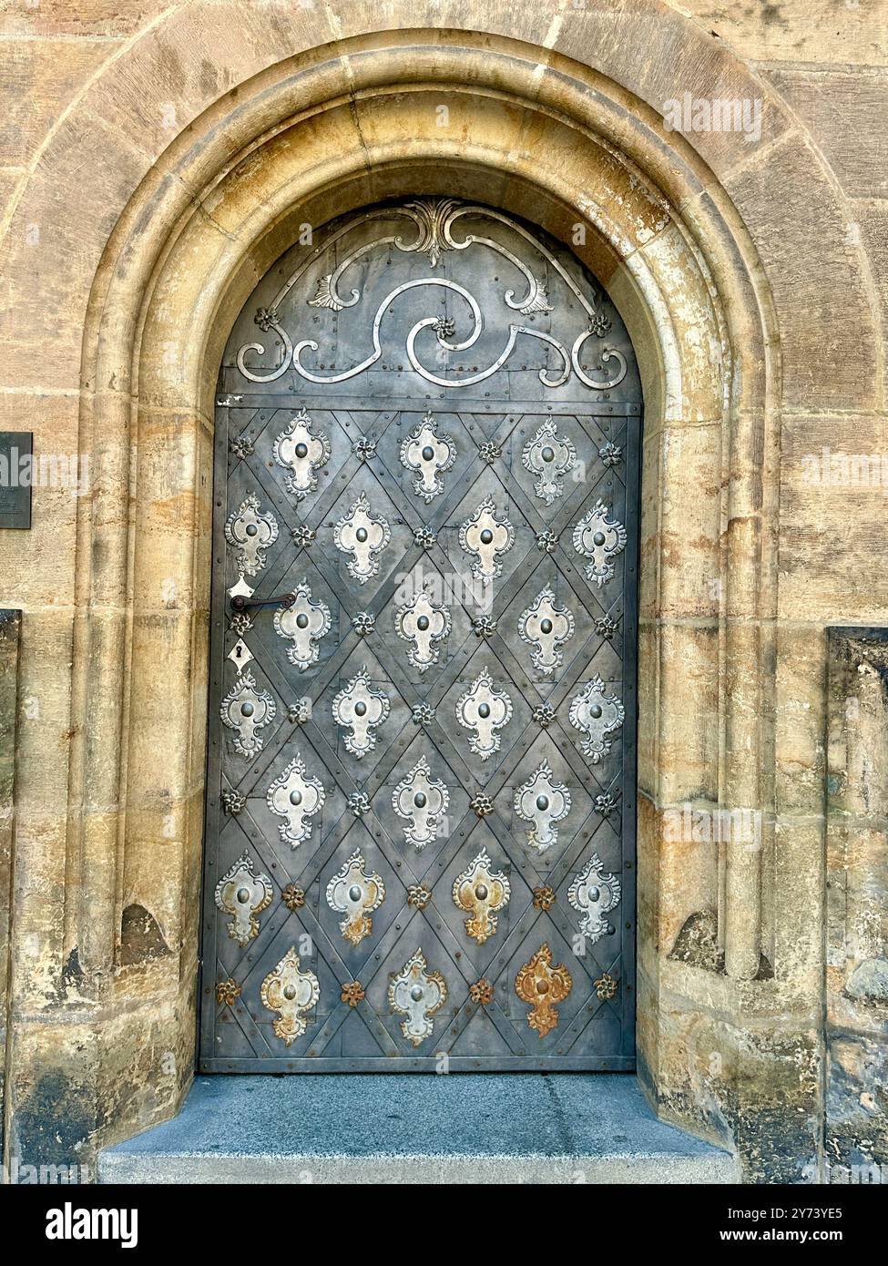 The photograph captures a detailed view of an old medieval gate made of wood and metal, set in the streets of a historic European city. - Smartphone Captured Stock Image