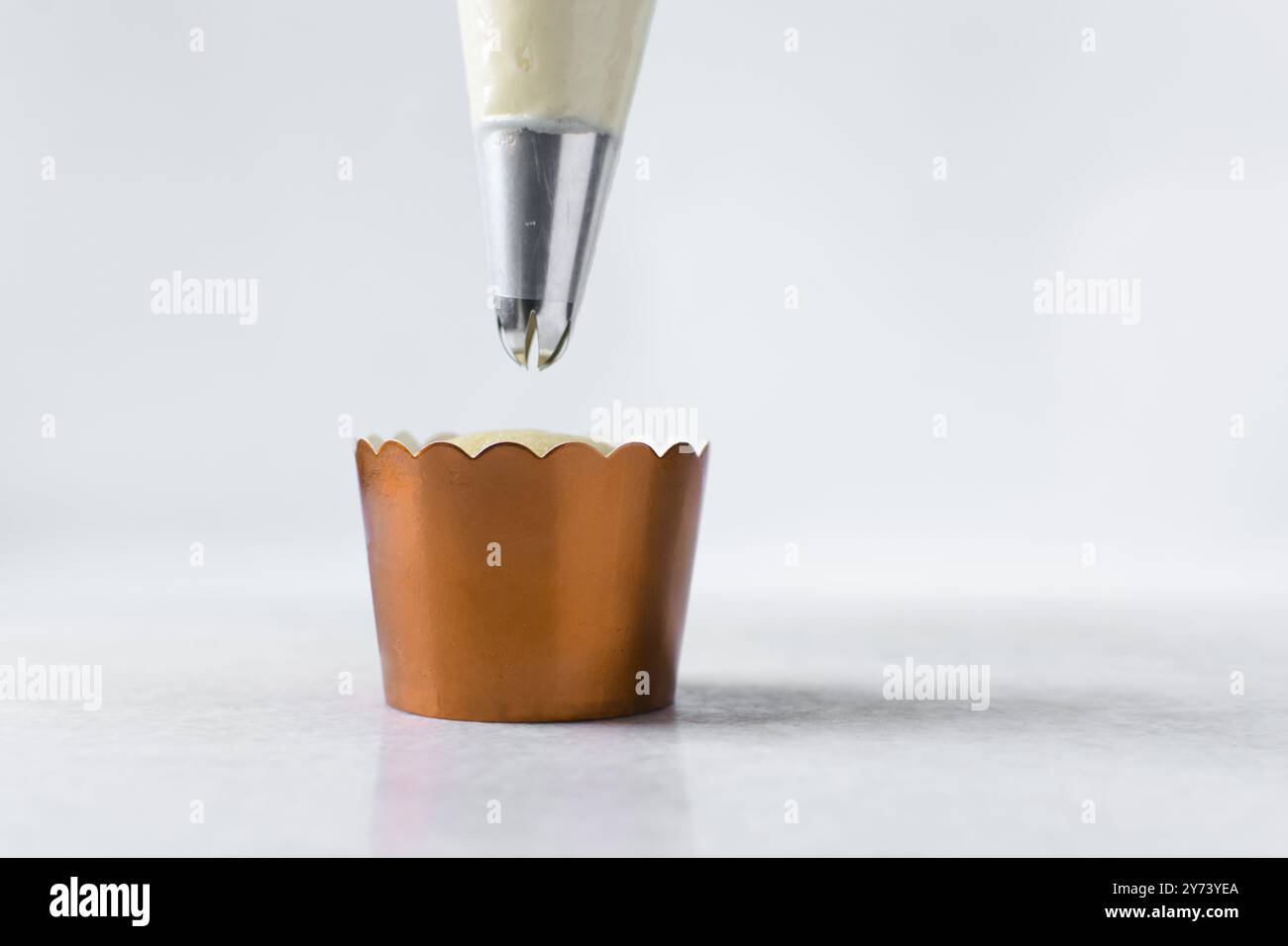 Piping buttercream on a cupcake, decorating cupcakes, hand piping tall frosting on cupcakes, the process of decorating cupcake Stock Photo