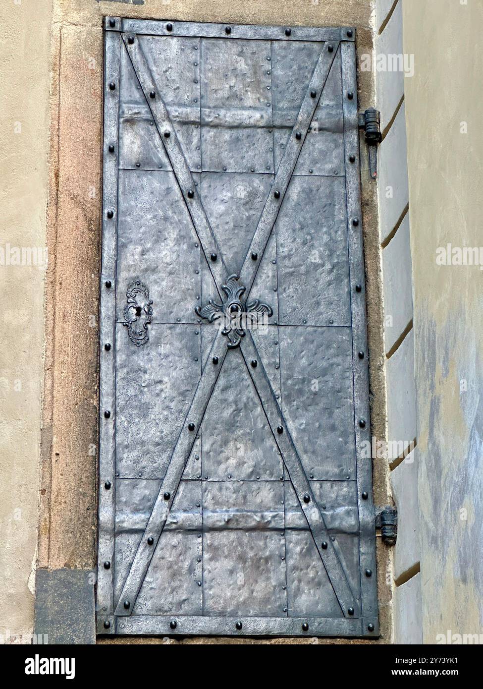 The photograph captures a detailed view of an old medieval gate made of wood and metal, set in the streets of a historic European city. - Smartphone Captured Stock Image