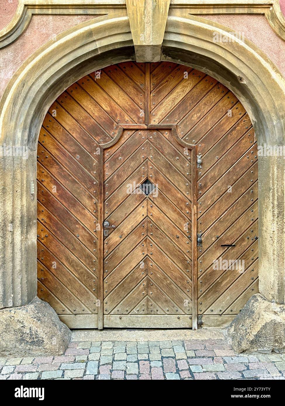 The photograph captures a detailed view of an old medieval gate made of wood and metal, set in the streets of a historic European city. - Smartphone Captured Stock Image