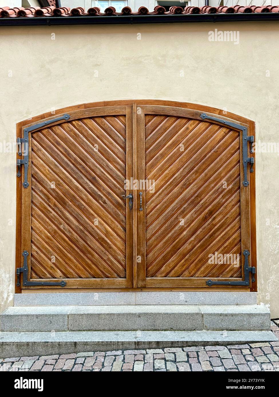The photograph captures a detailed view of an old medieval gate made of wood and metal, set in the streets of a historic European city. - Smartphone Captured Stock Image