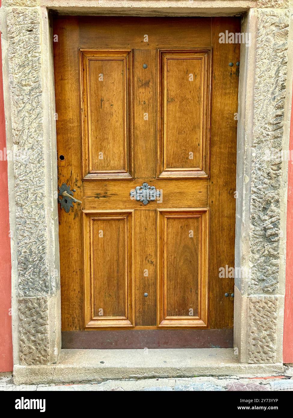 The photograph captures a detailed view of an old medieval gate made of wood and metal, set in the streets of a historic European city. - Smartphone Captured Stock Image