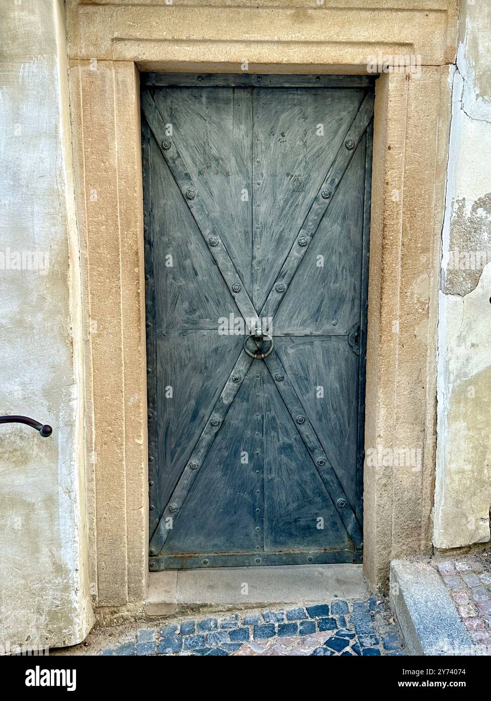 The photograph captures a detailed view of an old medieval gate made of wood and metal, set in the streets of a historic European city. - Smartphone Captured Stock Image