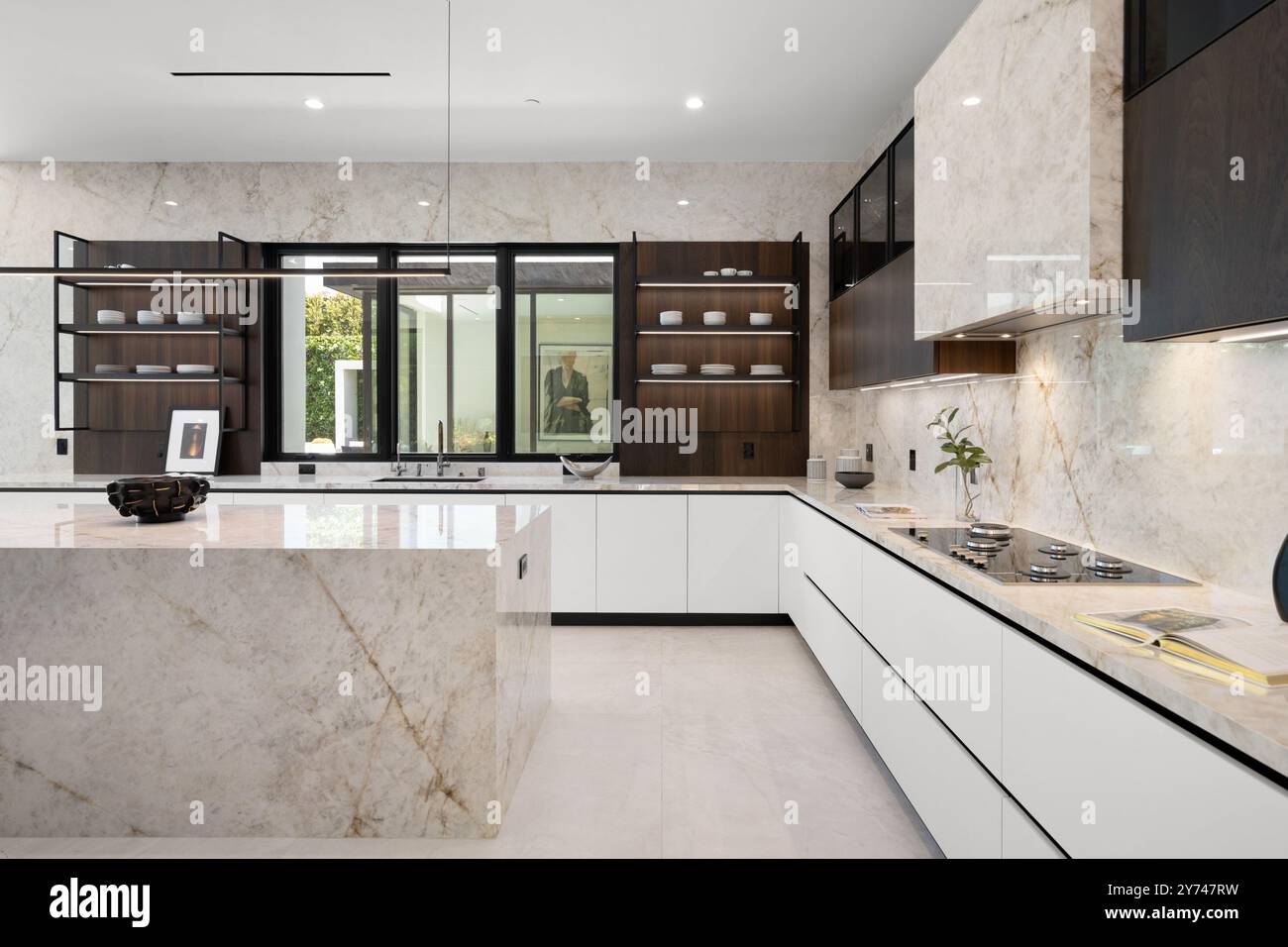 Modern kitchen with marble countertops, white cabinets, and open ...