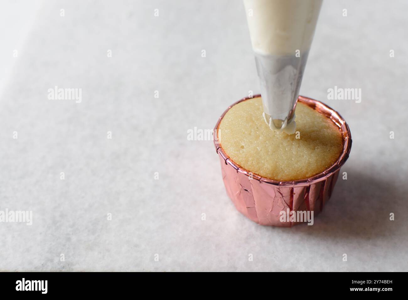Piping buttercream on a cupcake, decorating cupcakes, hand piping tall frosting on cupcakes, the process of decorating cupcake Stock Photo