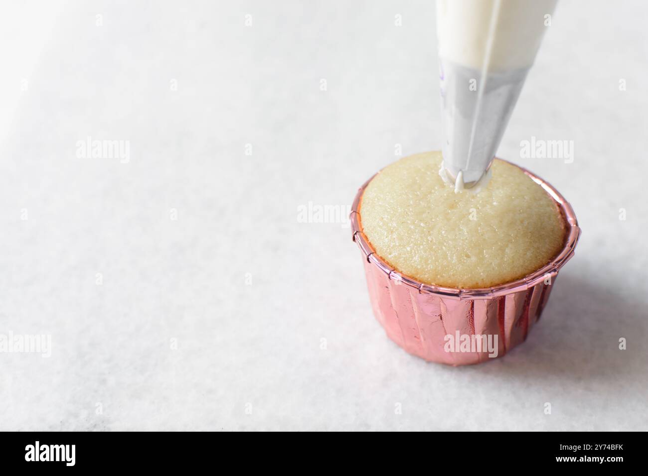 Piping buttercream on a cupcake, decorating cupcakes, hand piping tall frosting on cupcakes, the process of decorating cupcake Stock Photo