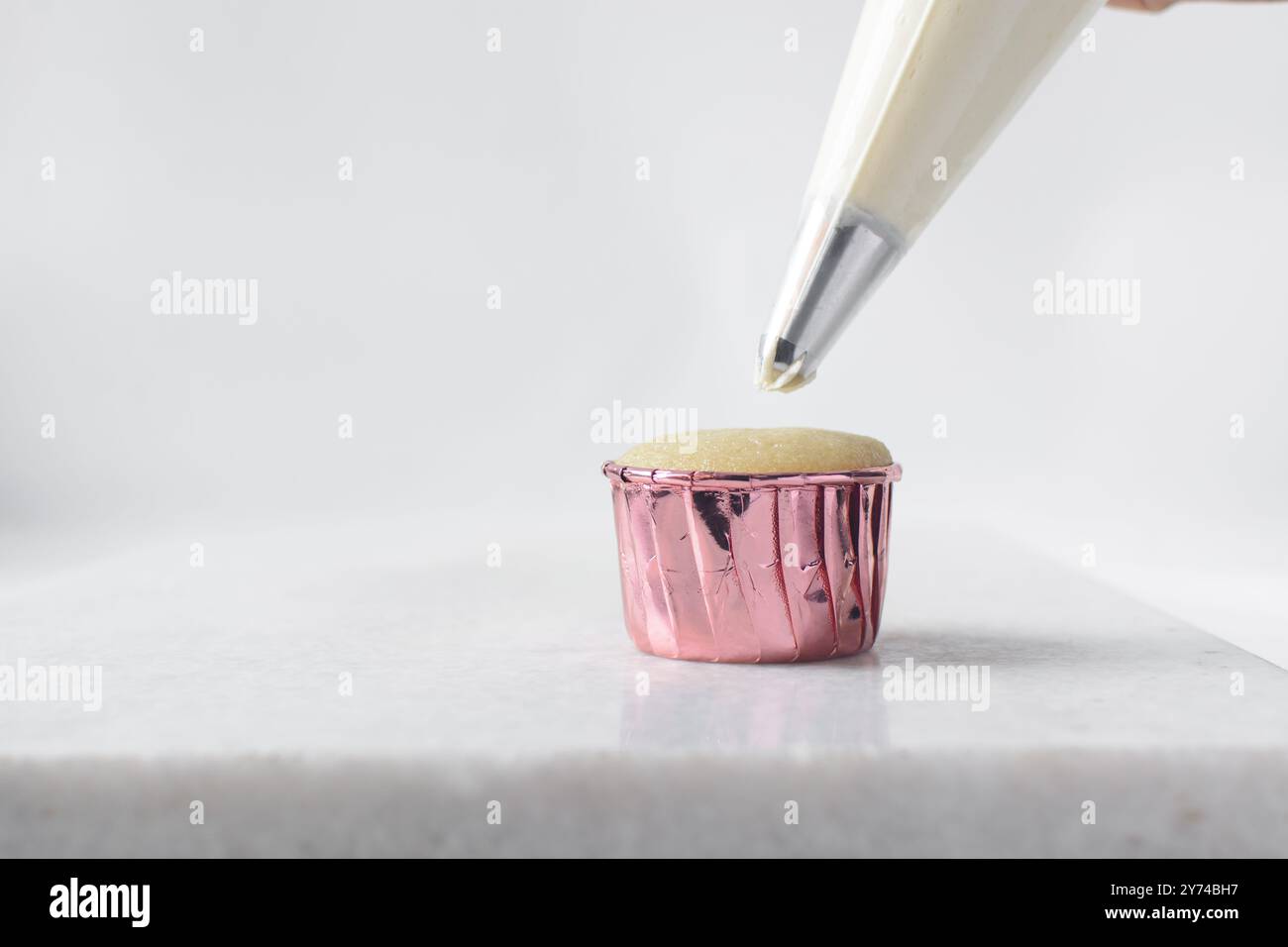 Piping buttercream on a cupcake, decorating cupcakes, hand piping tall frosting on cupcakes, the process of decorating cupcake Stock Photo