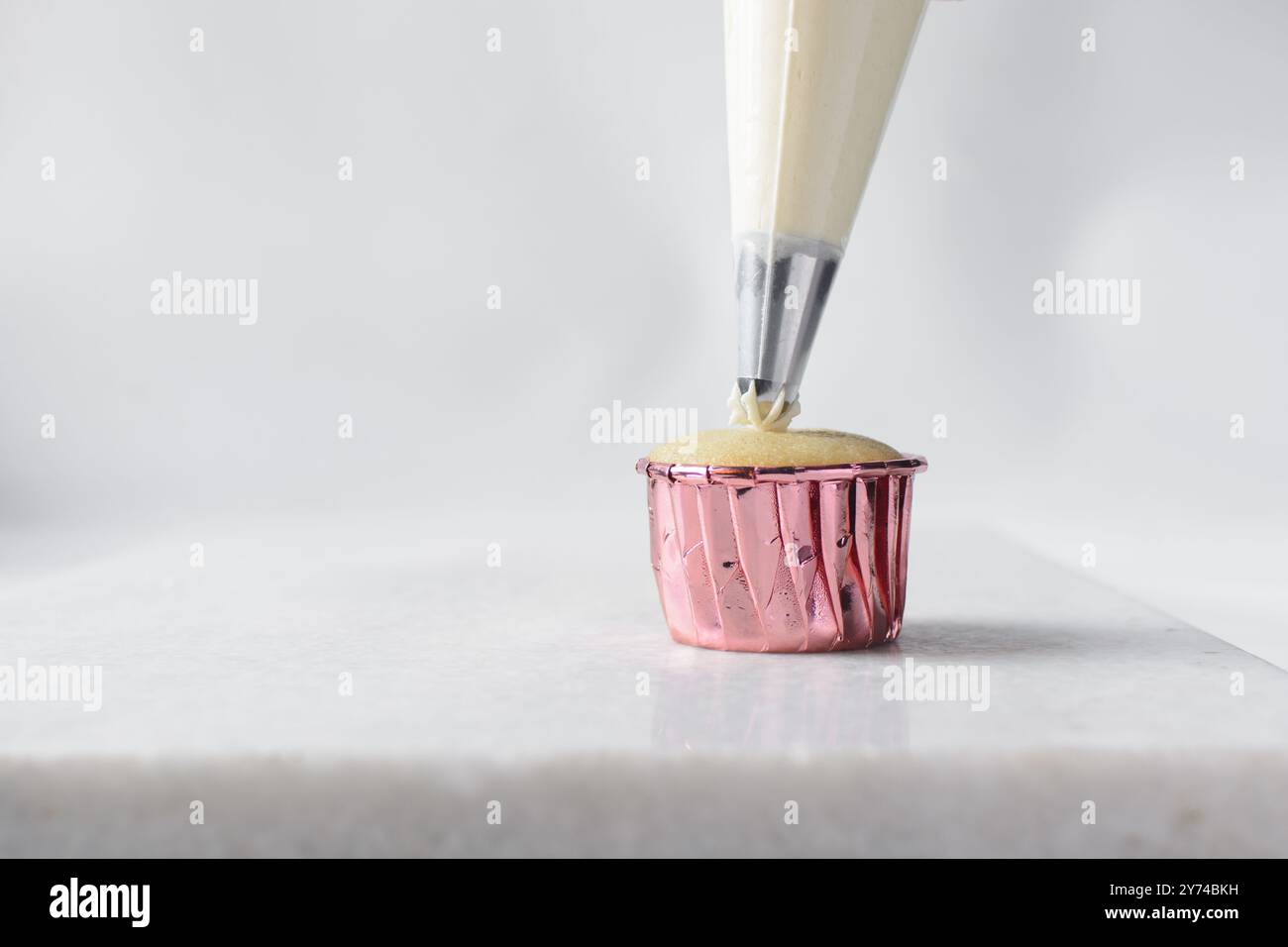 Piping buttercream on a cupcake, decorating cupcakes, hand piping tall frosting on cupcakes, the process of decorating cupcake Stock Photo