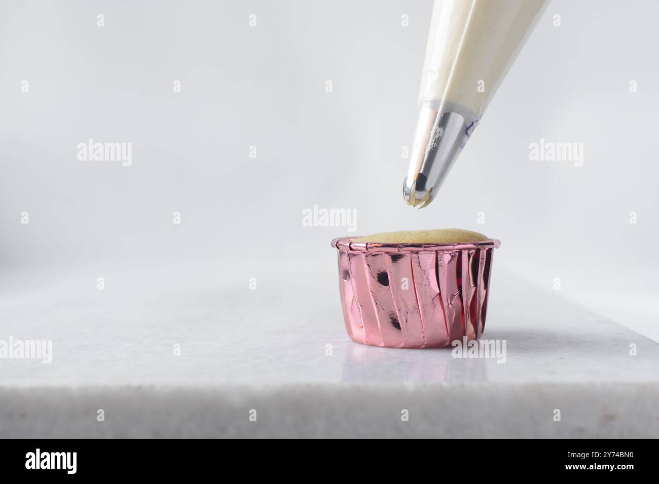 Piping buttercream on a cupcake, decorating cupcakes, hand piping tall frosting on cupcakes, the process of decorating cupcake Stock Photo