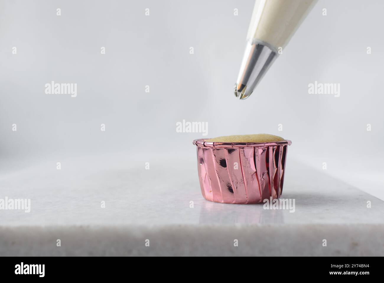 Piping buttercream on a cupcake, decorating cupcakes, hand piping tall frosting on cupcakes, the process of decorating cupcake Stock Photo