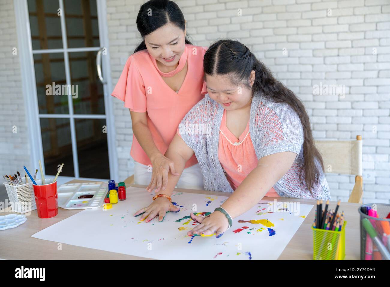 A mother and daughter happily doing art activities together at home ...