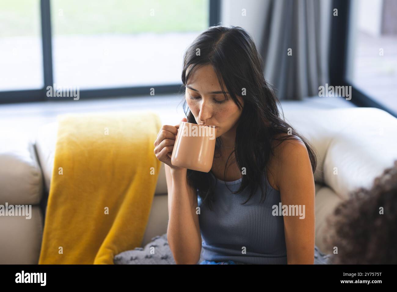 Drinking coffee, woman relaxing on couch during diverse friends hangout at home Stock Photo