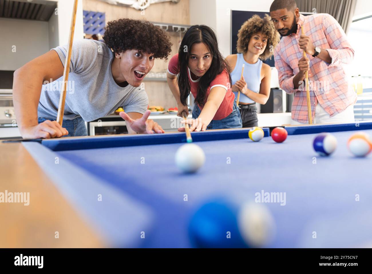 Playing pool, group of diverse friends enjoying leisure time and having ...