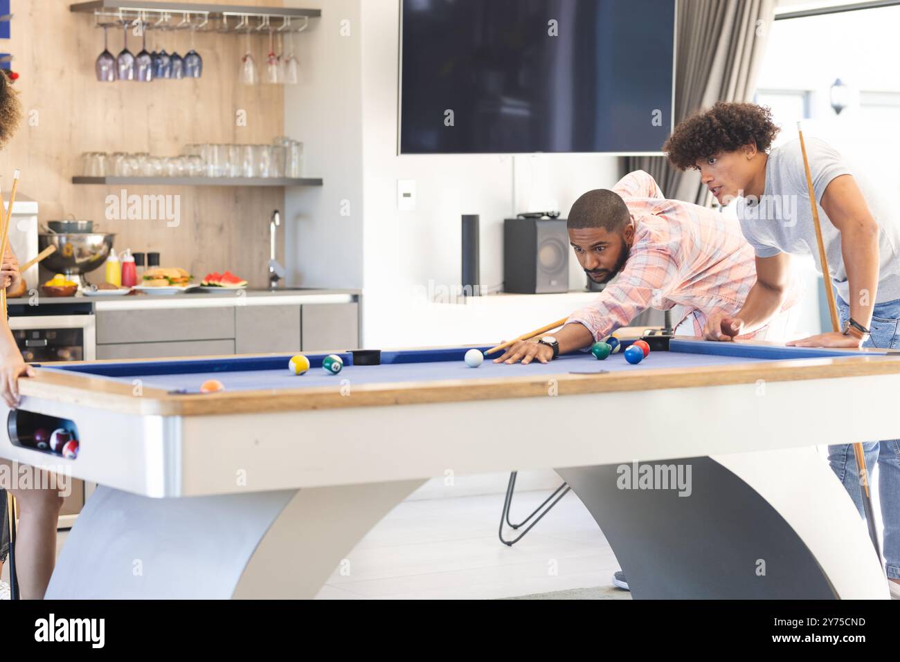 Playing pool, diverse friends enjoying game together in modern living room, at home Stock Photo