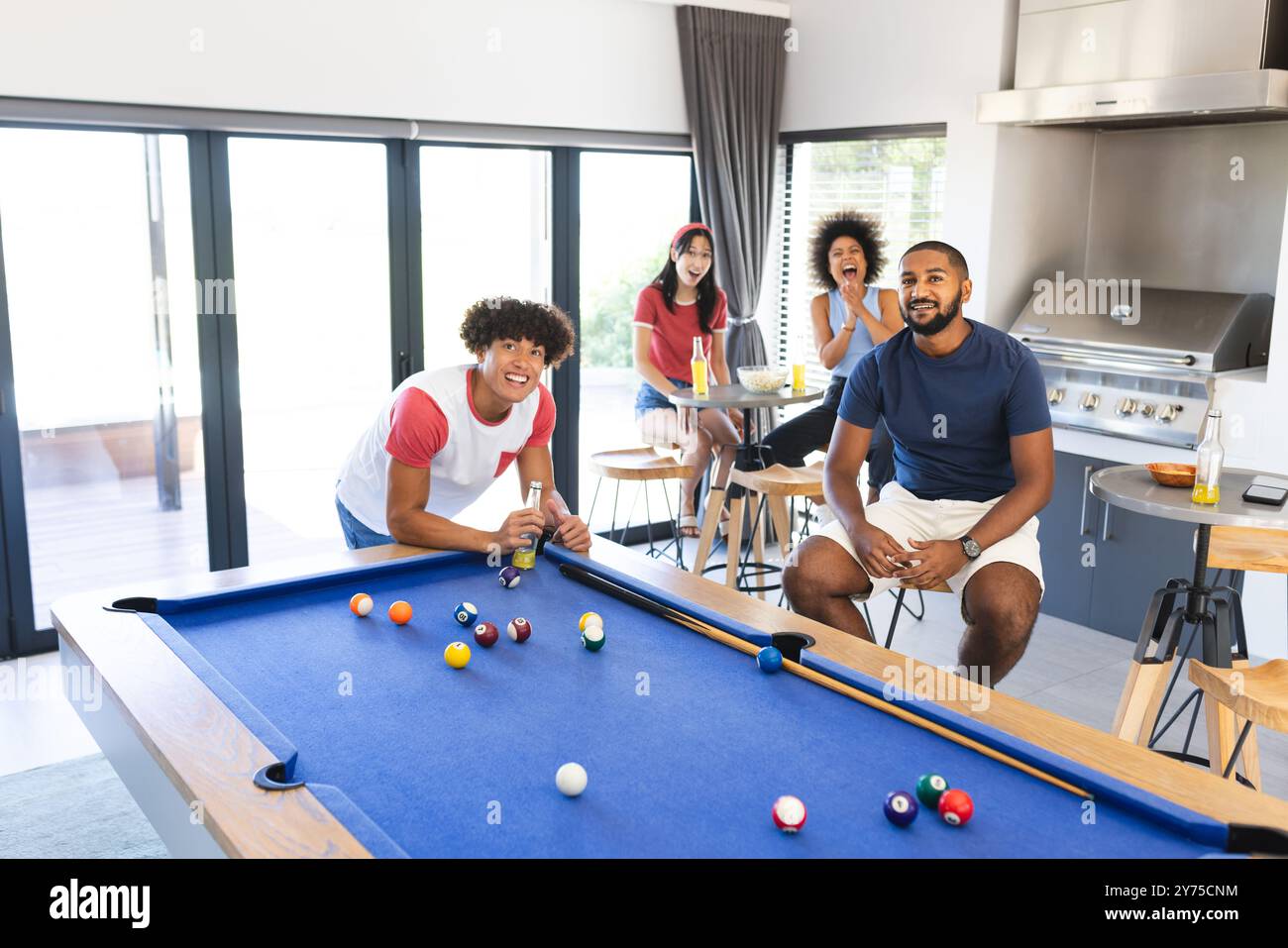 Playing pool, diverse friends enjoying drinks and socializing in modern ...