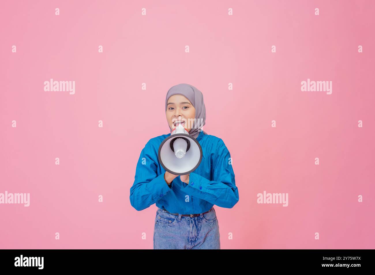 A Young Woman with a Megaphone is Passionately Expressing Her Ideas Against a Bright Pink Background Stock Photo