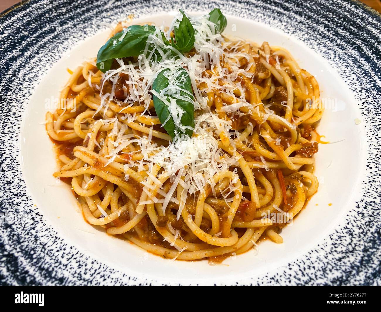 A plate of spaghetti bolognese with parmesan cheese grated on top at an Italian restaurant - Smartphone Captured Stock Image