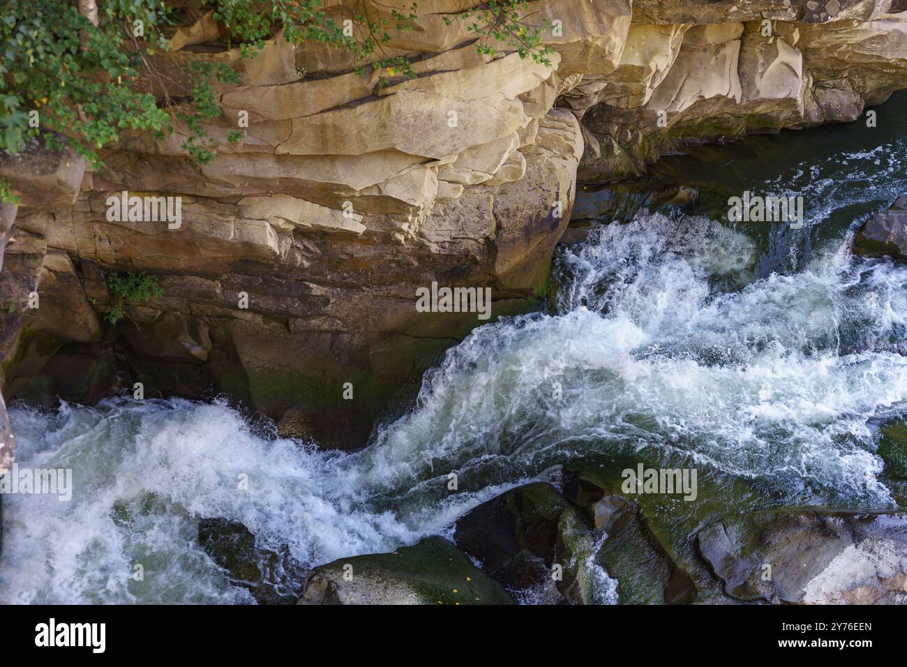 Closeup texture of rapid river with fresh cold water flowing through mountain rocks with foam and bubbles on sunny day. Nature force and power backgro Stock Photo