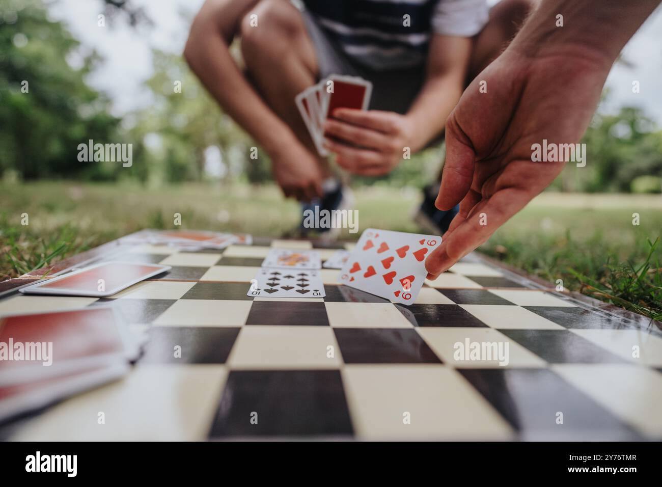 Playing cards on a chess board in a park setting Stock Photo - Alamy