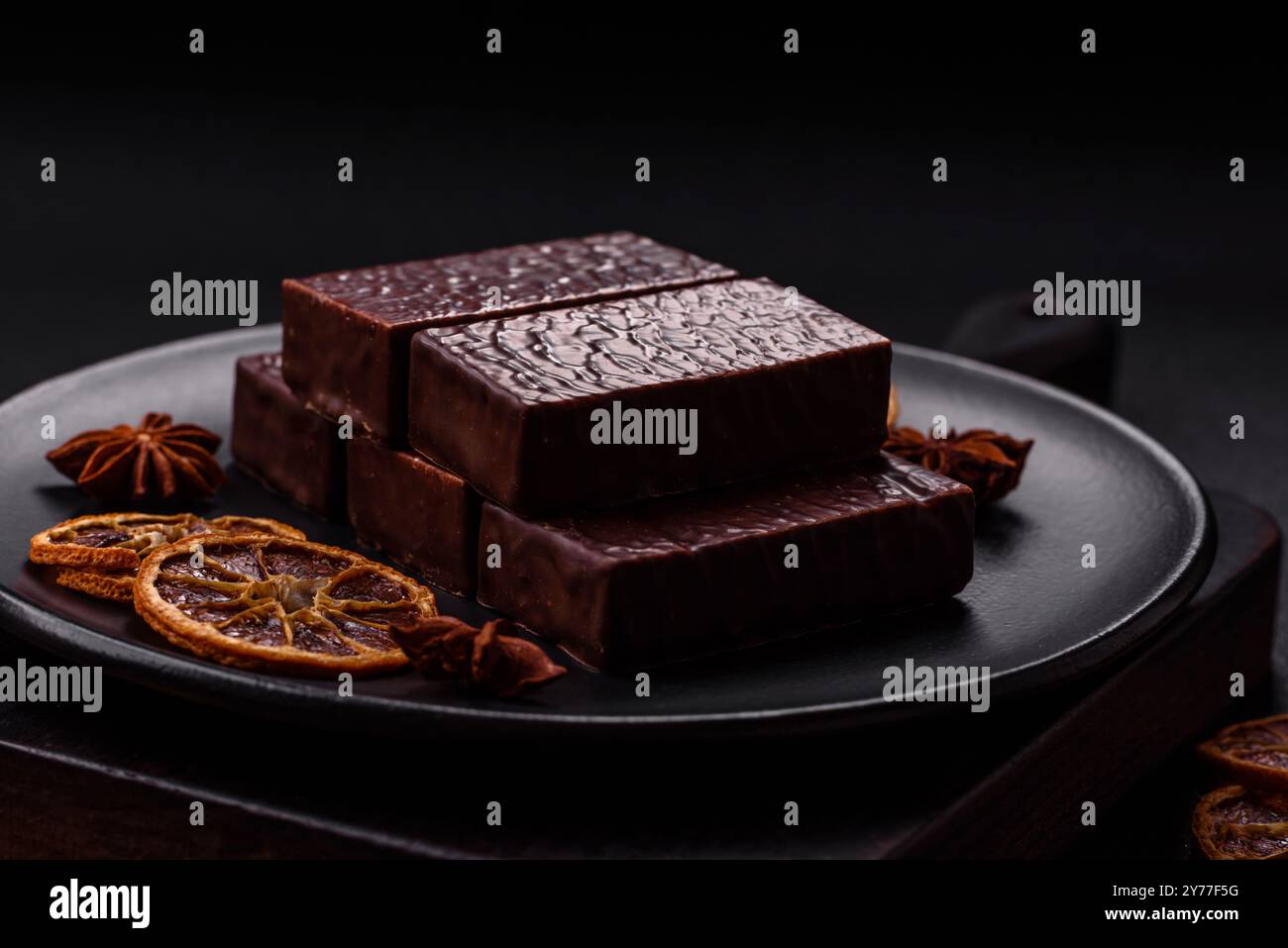 Rectangular chocolate candies with mousse and waffles on a dark ...