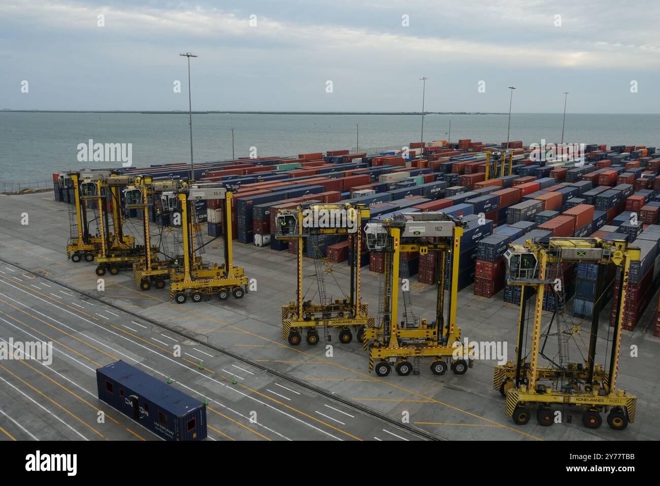 Straddle carriers are lined up at the Kingston Freeport container terminal, poised beneath gantry crane. Stock Photo