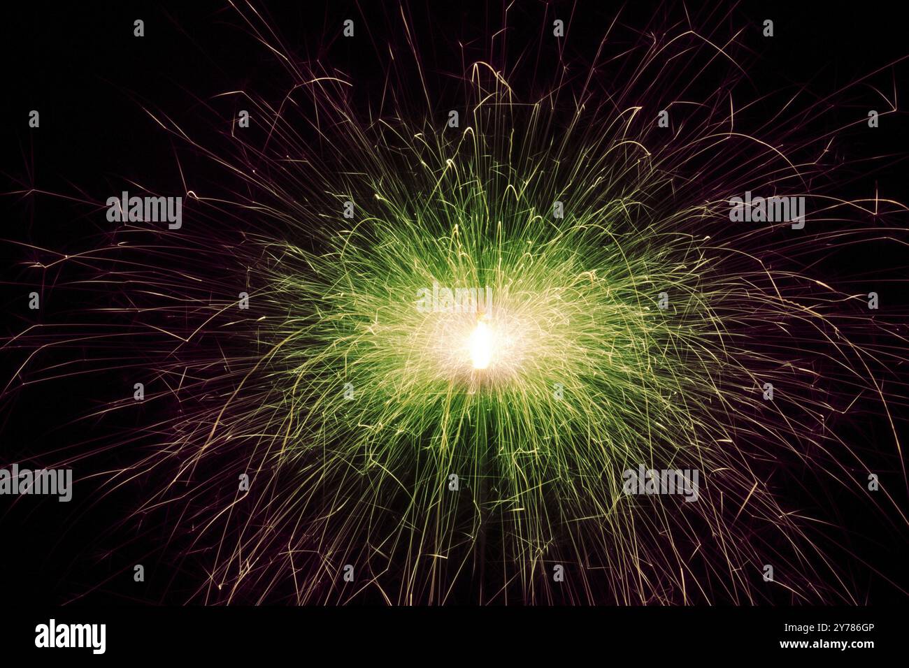 Red and green sparks of a festive New Year's light. Sparks fly in different directions from the burning sparkler Stock Photo