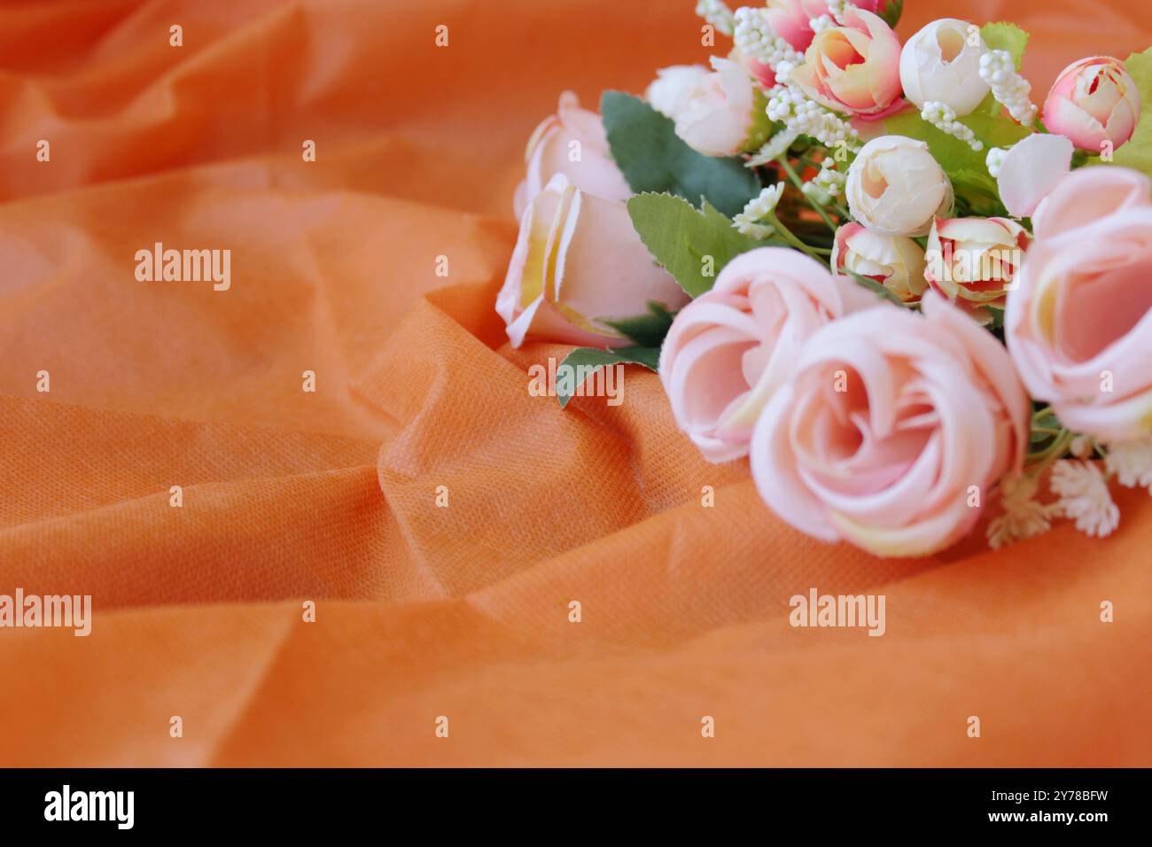 Orange color fabric background with romantic delicate pink roses. Copy ...