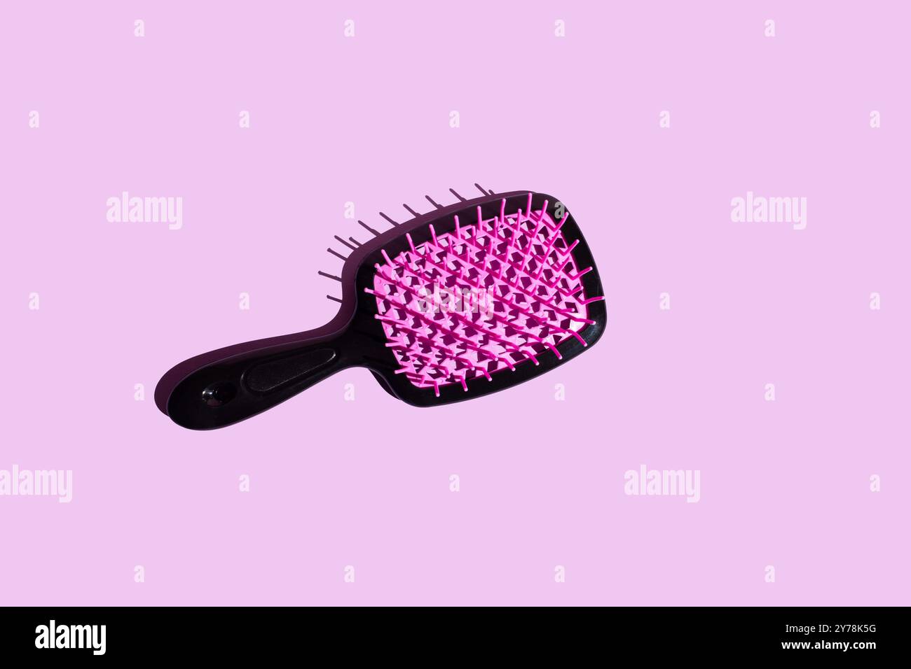 Vibrant Elegance top view of a hairbrush resting on a vibrant pink surface, adorned with a captivating lattice pattern in neon pink and deep black ton Stock Photo