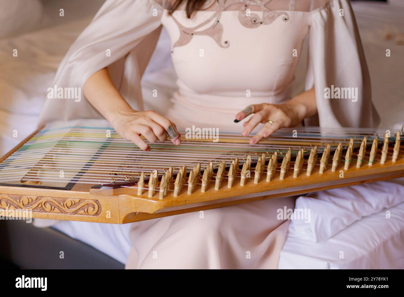 Close-up of a woman playing a traditional string instrument, wearing a ...