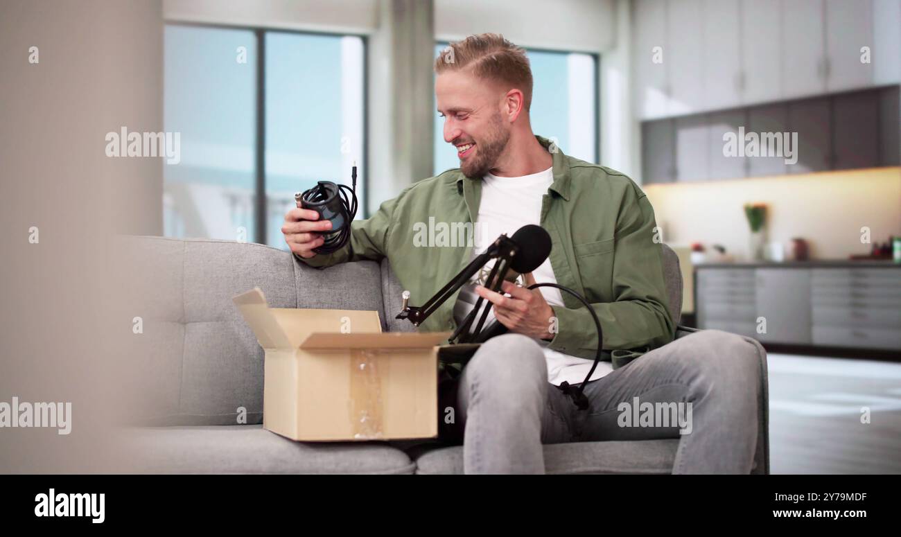 Smiling Young Man Sitting On Sofa Unpacking Received Parcel Stock Photo