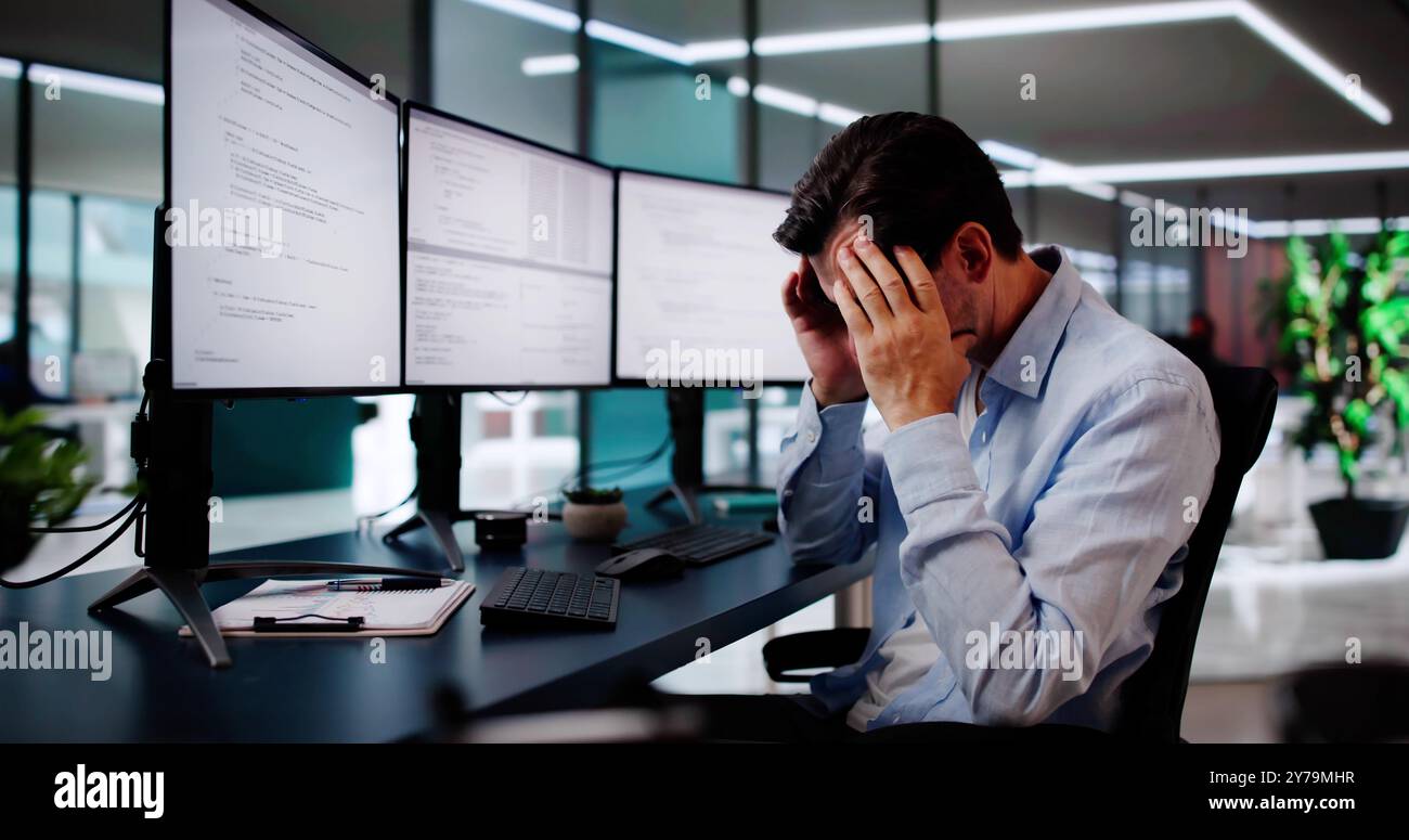 Unhappy Sad Developer Programmer Man In Stress Coding Software On Computer Stock Photo