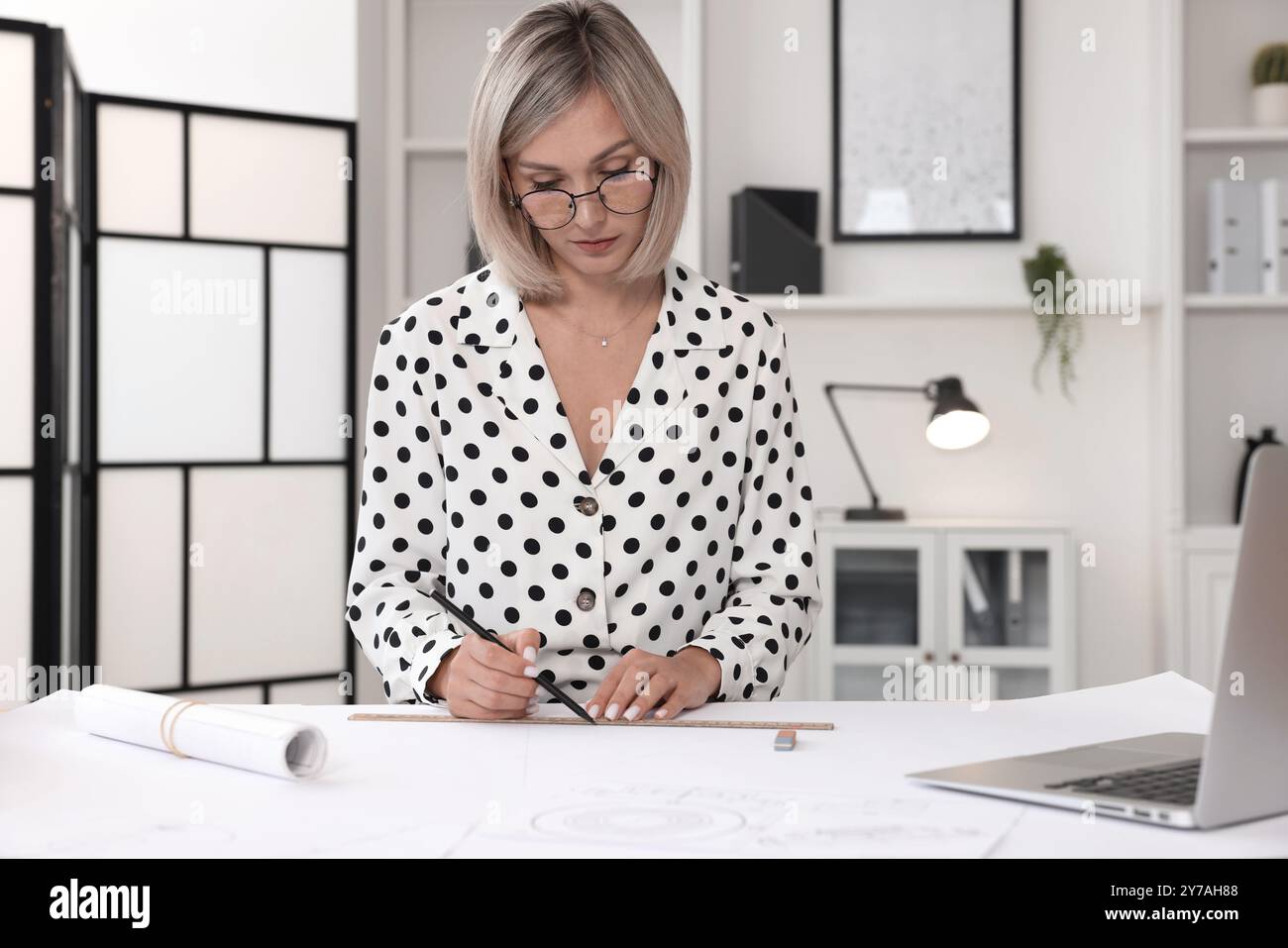 Architect making engineering drawing at table in office Stock Photo
