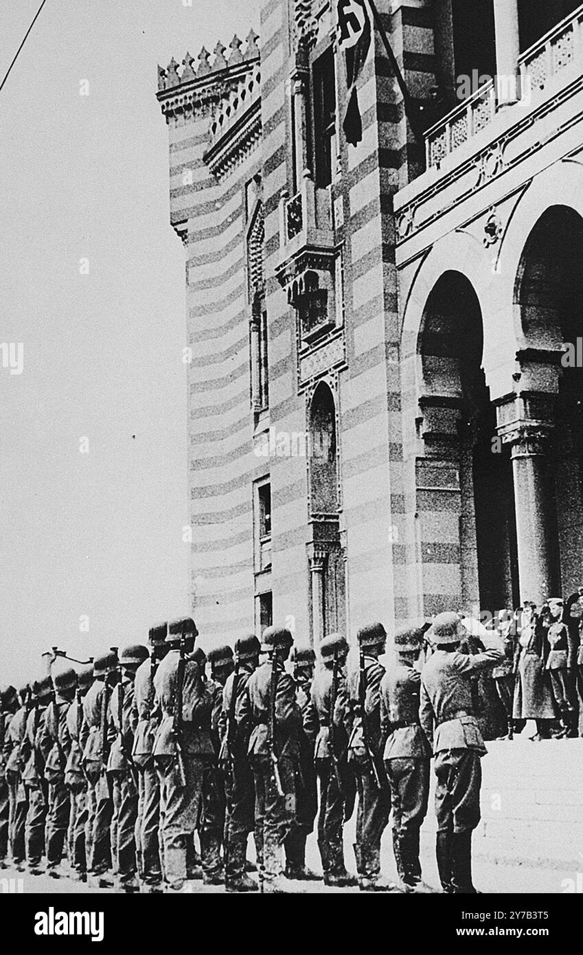 German troops salute during a flag raising ceremony on the balcony of Sarajevo city hall. The nazi occupation of Greece (to bail out Mussolini's botched attempt) and of Yugoslavia (to crush resistance) were quick but took over a month. It makes interesting speculation to imagine if they had not been sidetracked in the Balkans and had launched Barbarossa a month earlier. Would Moscow have fallen before the onset of winter? Stock Photo