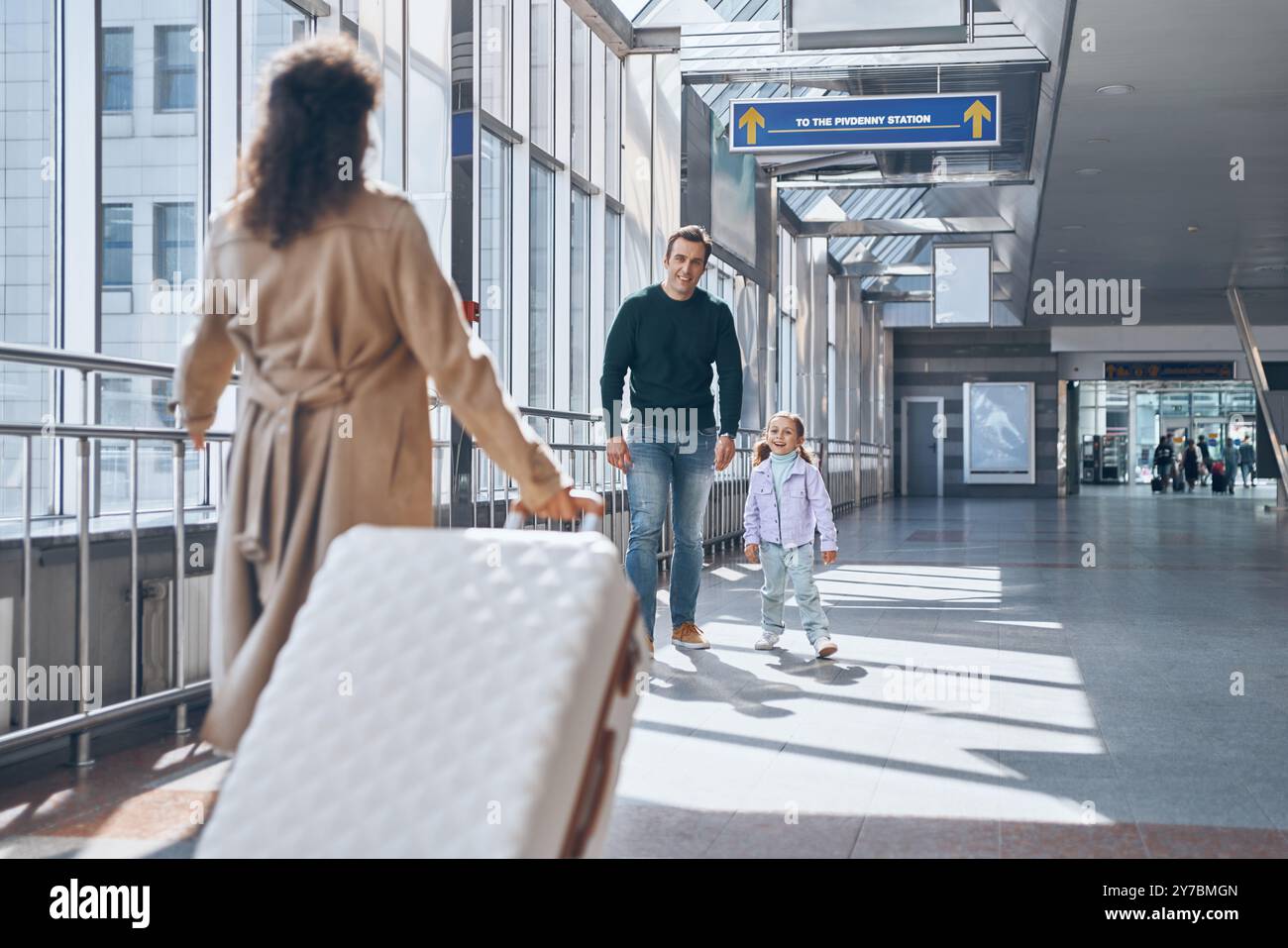 Happy father with little girl meeting wife at the airport terminal ...