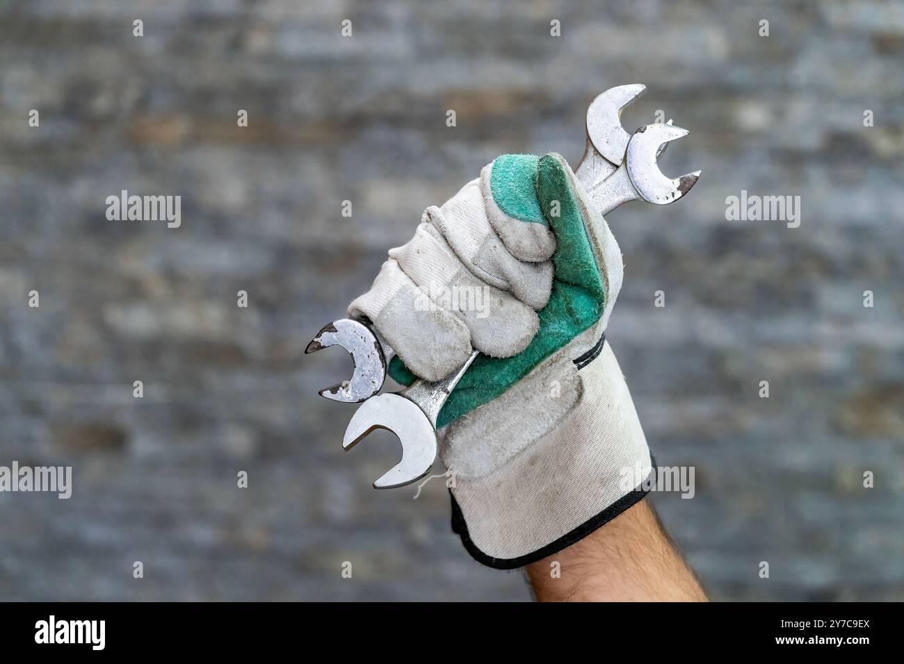Close-up shot of a gloved hand holding multiple open end wrenches Stock Photo
