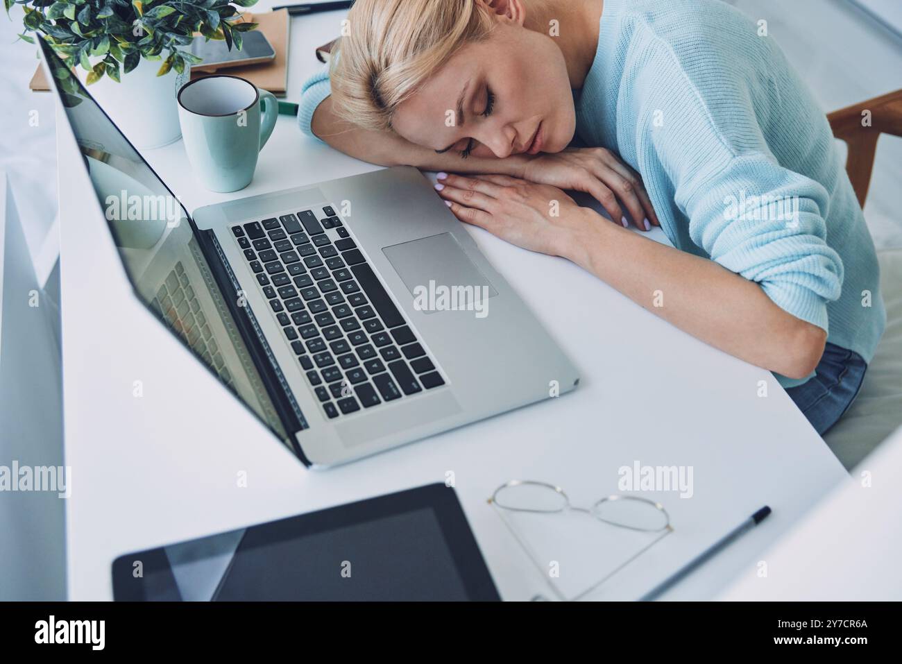 top-view-of-tired-young-woman-sleeping-while-sitting-at-her-working