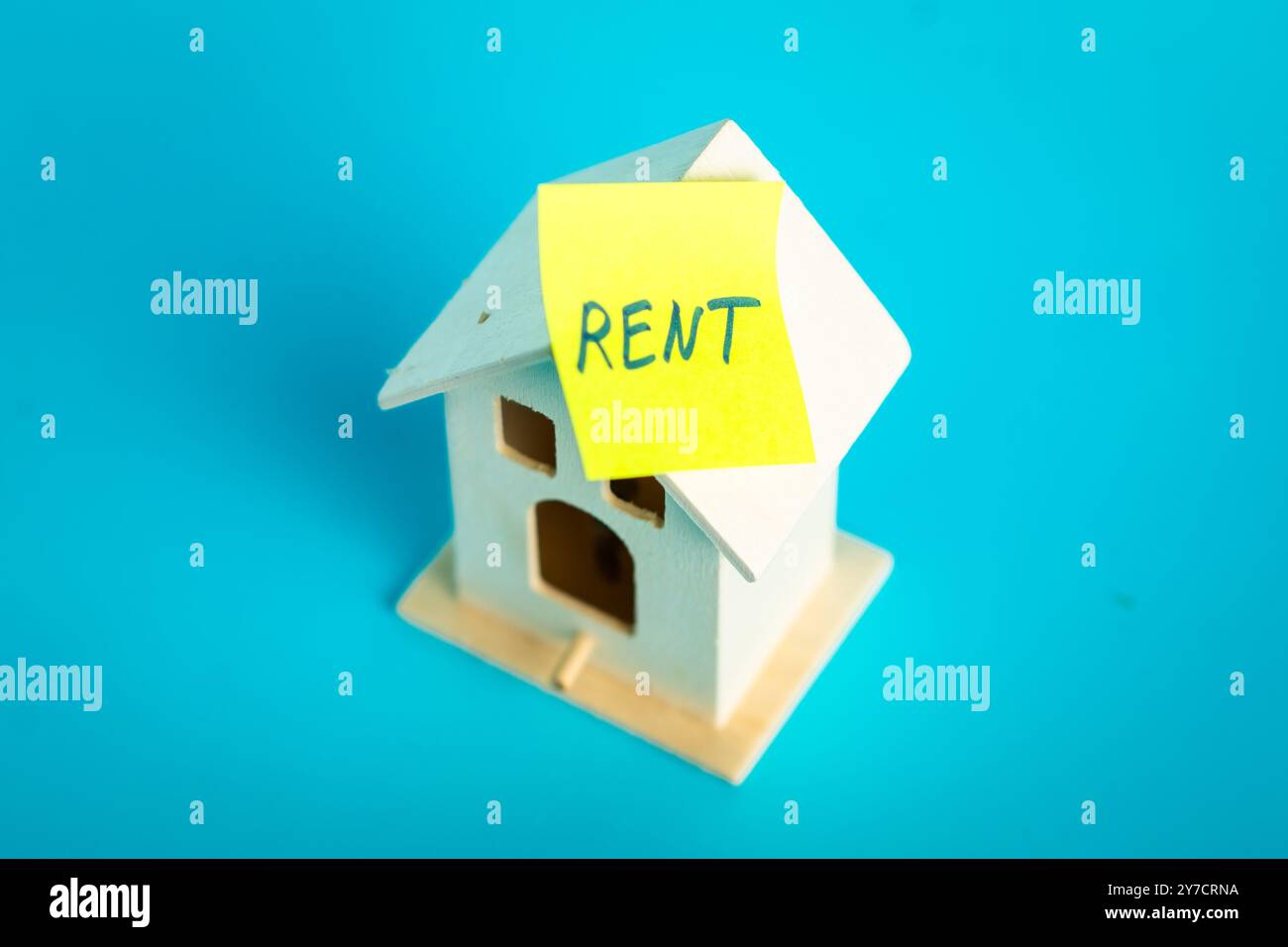 Miniature house with rent note on turquoise background symbolizing ...