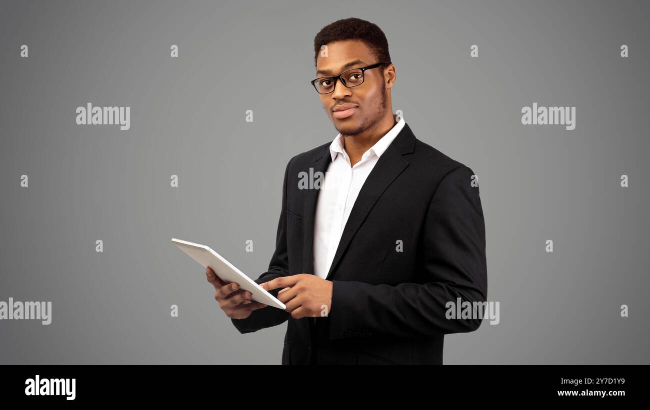 Black guy in suit standing with tablet Stock Photo