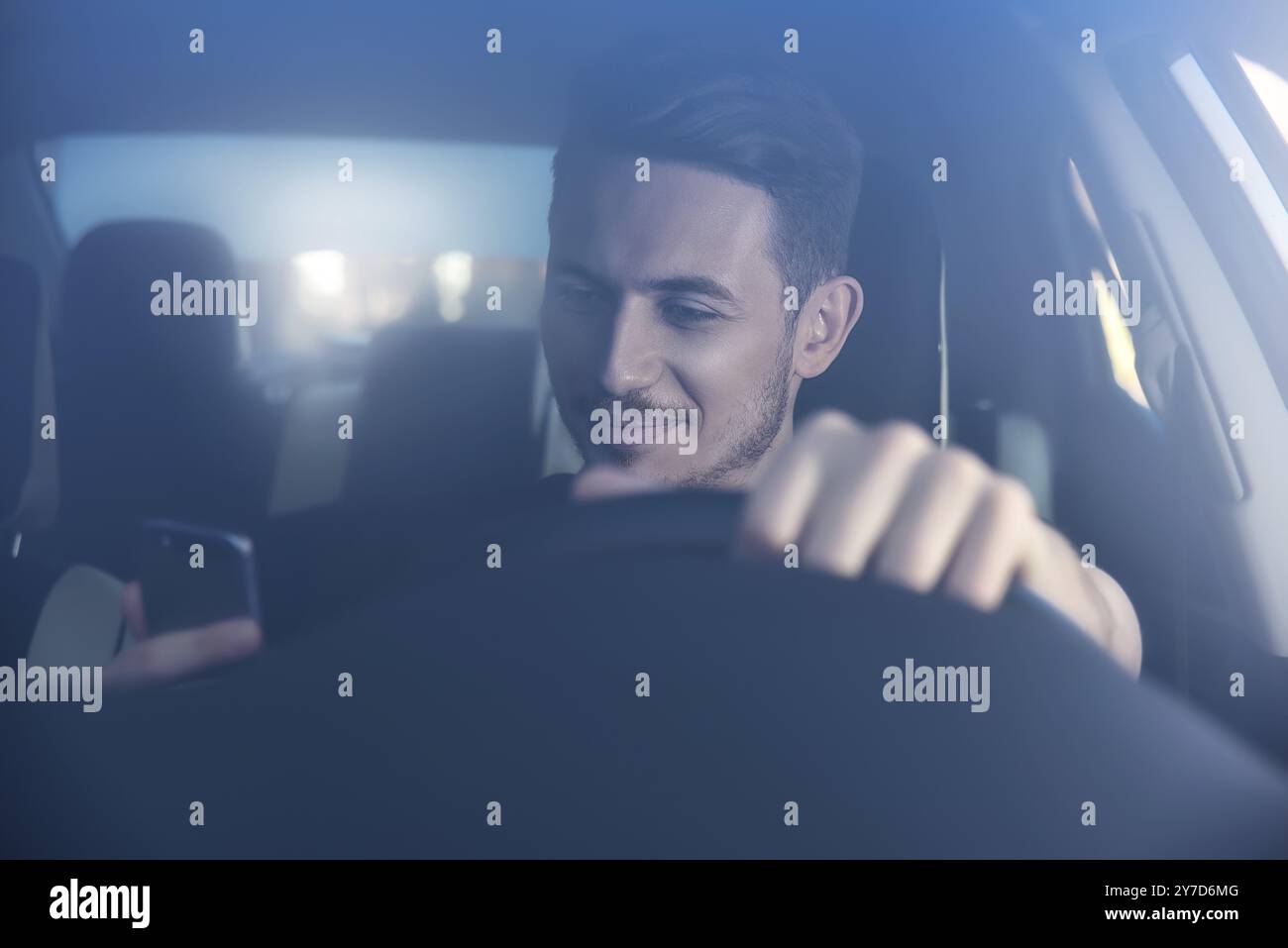 Businessman texting on his mobile phone while driving. Dangerous driver Stock Photo