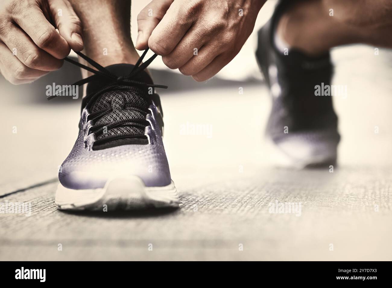 Cropped image of hands tying shoelaces on sneaker, running surface background. Hands of sportsman with pedometer tying shoelaces on sporty sneaker. Ru Stock Photo