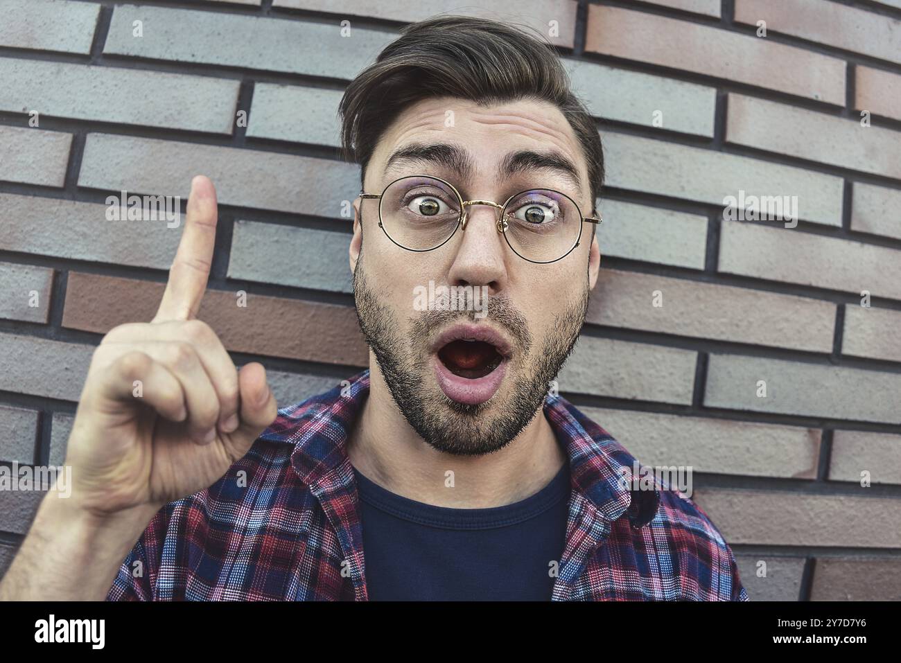 Great idea! Handsome man keeping finger pointed upwards, showing something above his head, making gesture with index finger. Eureka, solution sign con Stock Photo
