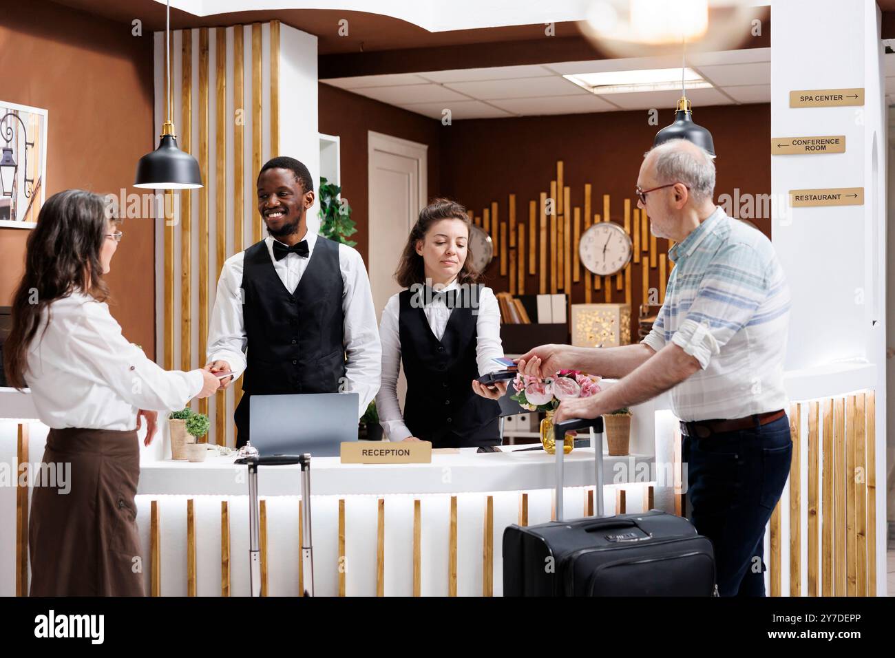 Elderly couple at hotel reception where friendly staff assist with ...