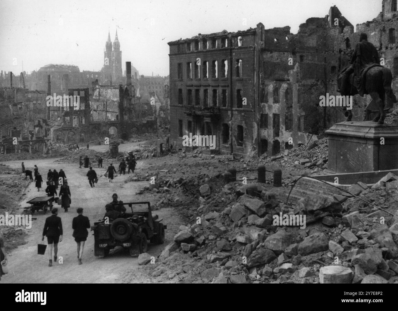 People walking in a wrecked street in the bombed-out city of Nuremberg.     Visible in the distance is the twin-spired Lorenz Church, and on the right, a statue of Kaiser Wilhelm I. Stock Photo