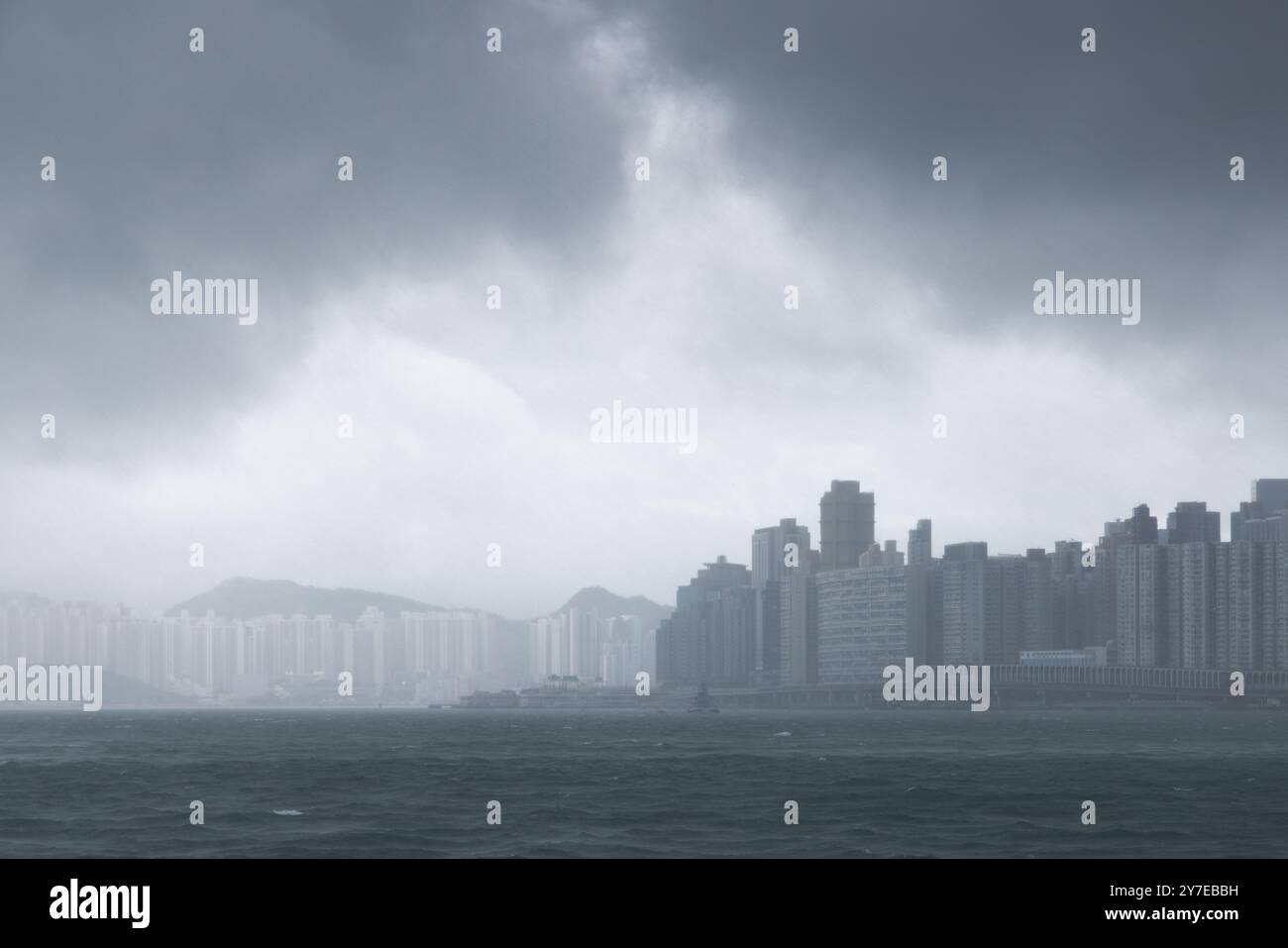 A stormy view of Hong Kong’s high-rise buildings under dark, heavy clouds with rough waters, indicating a Typhoon Signal No. 8 and Black Rain warning on September 8, 2025.