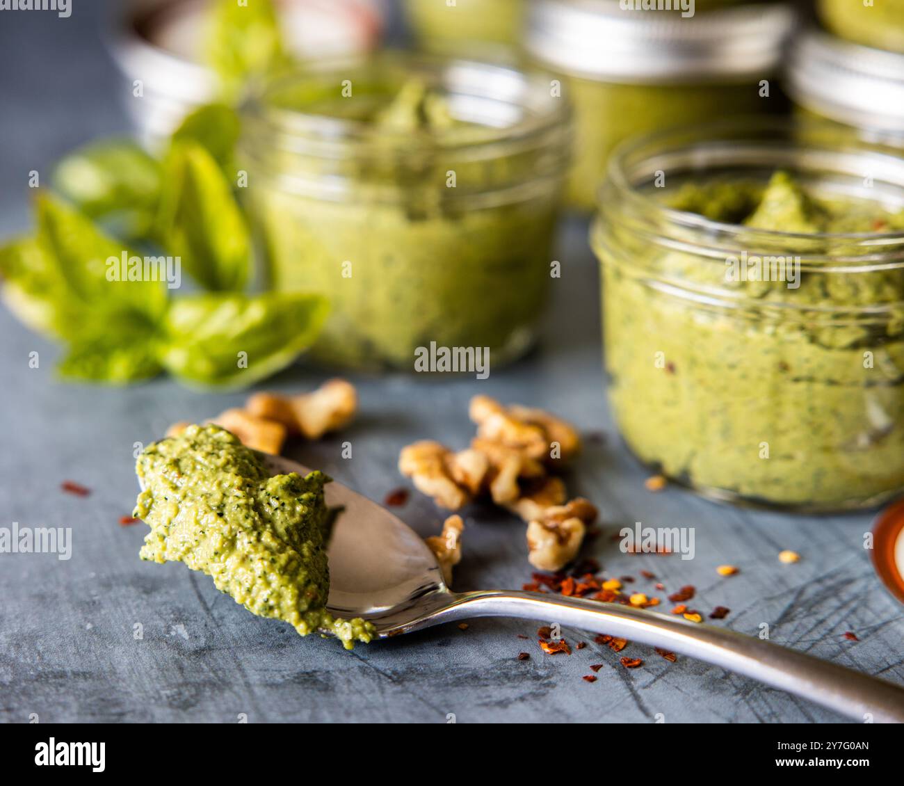 Basil Pesto on a spoon in front of glass jars Stock Photo
