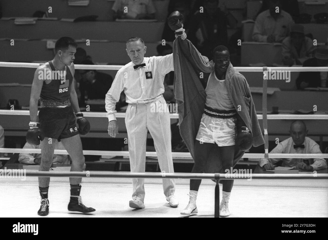 The referee holds aloft the arm of I Dabore , of the Niger Republic after he had scored a technical knockout over T F Hong ( left ) , of Taiwan in the first round welterweight Olympics boxing championships . The referee stopped the contest in the second round .   14th October 1964 Stock Photo