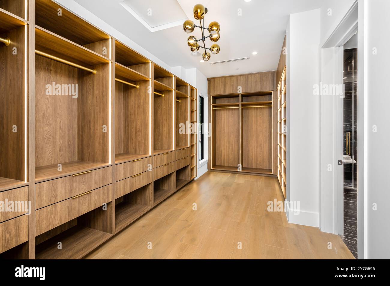 A modern walk-in closet with wooden shelves and drawers, featuring a ...