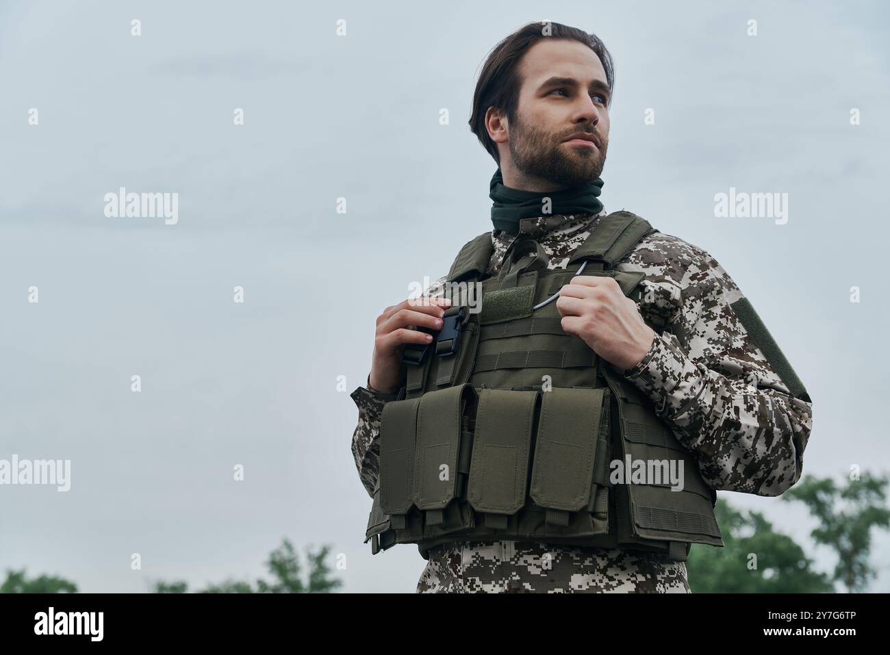Thoughtful young man in military uniform looking away while standing outdoors Stock Photo