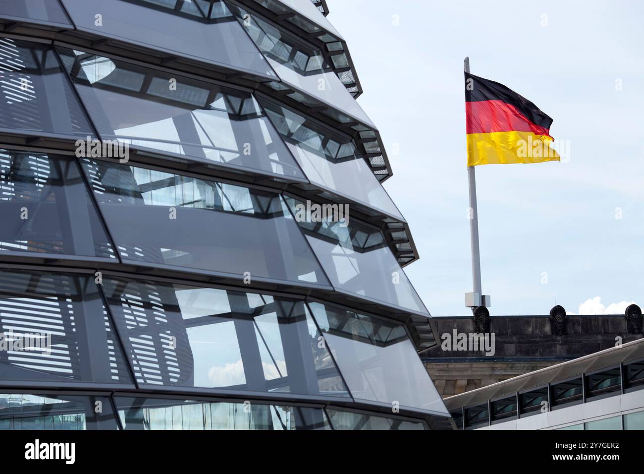 The iconic Reichstag roof dome showcases modern architecture while the German flag proudly waves in the background over Berlin. Stock Photo